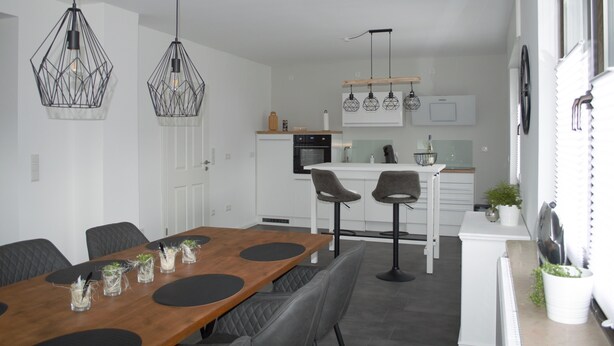 A modern kitchen with white cabinets, a central island, and pendant lighting. - Vacation home in Wehr Eifel, near Laacher See and Nürburgring with large garden (Wehr)