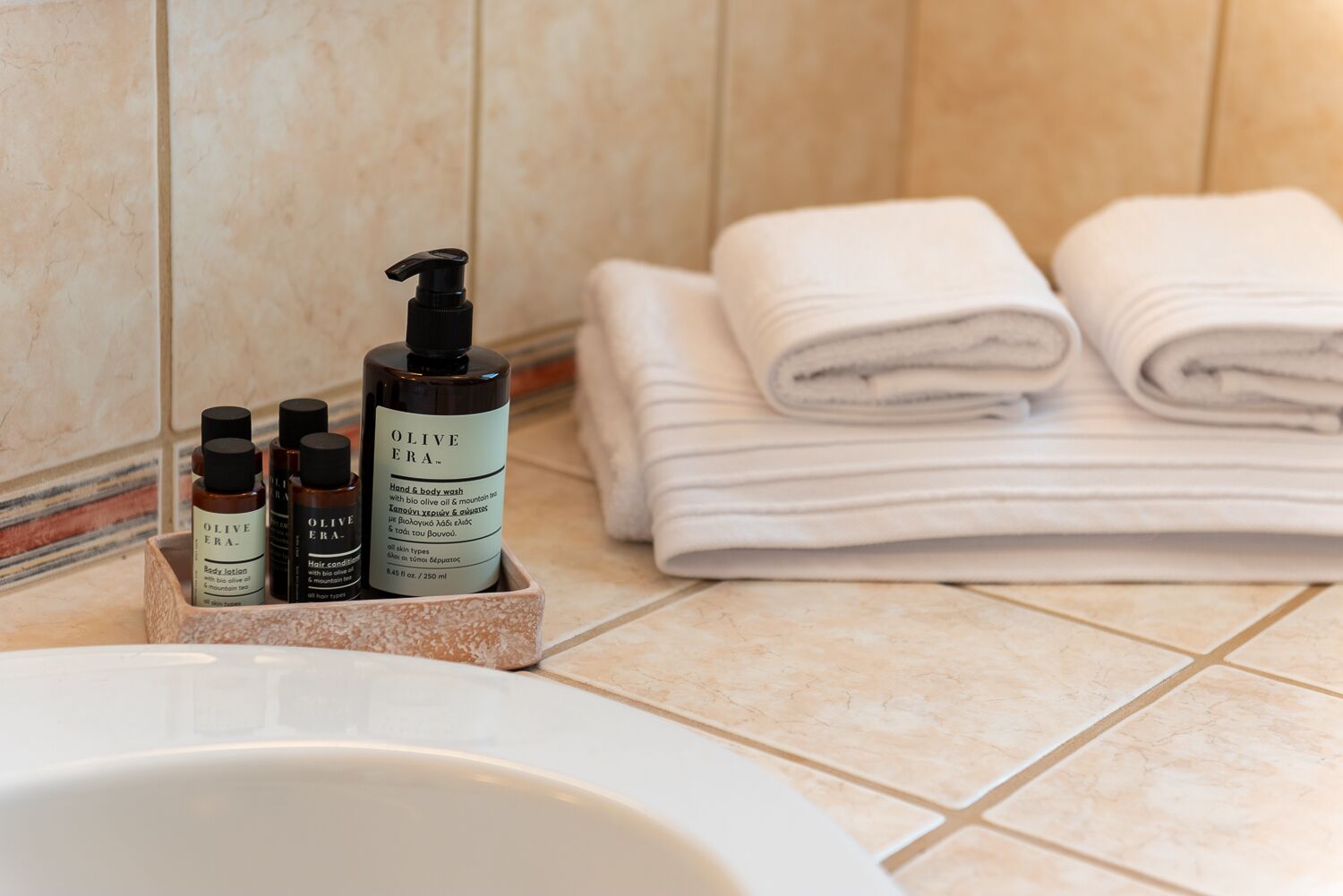 A bathroom with a sink, toiletries, and neatly folded towels.