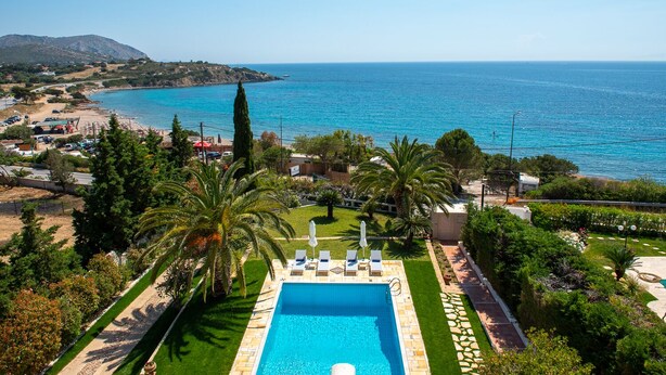 Una piscina con vista sul mare, circondata da vegetazione e un cielo sereno.