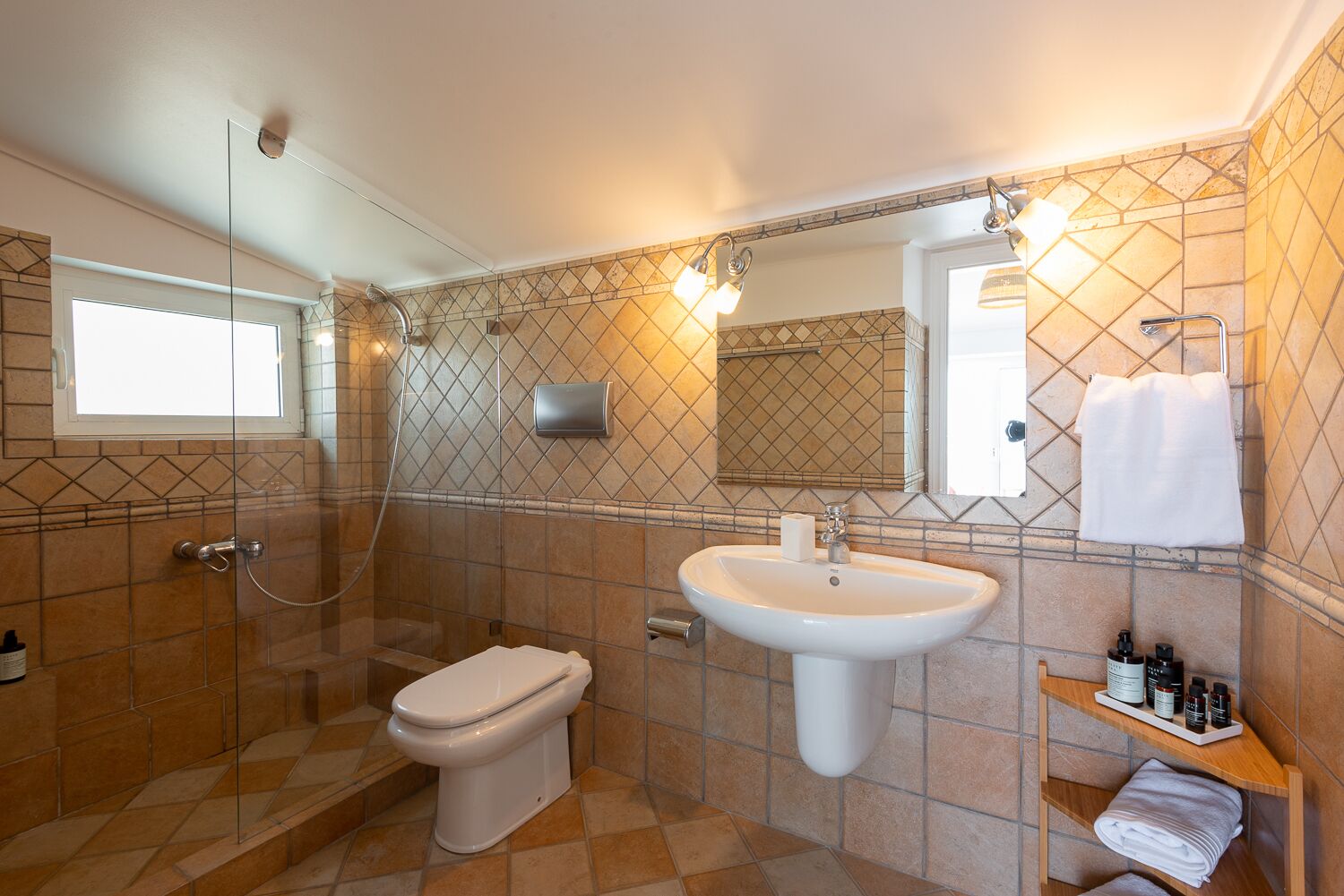 A bathroom with a glass-enclosed shower, a white sink, and a mirror above it.