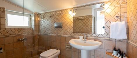 A bathroom with a glass-enclosed shower, a white sink, and a mirror above it.