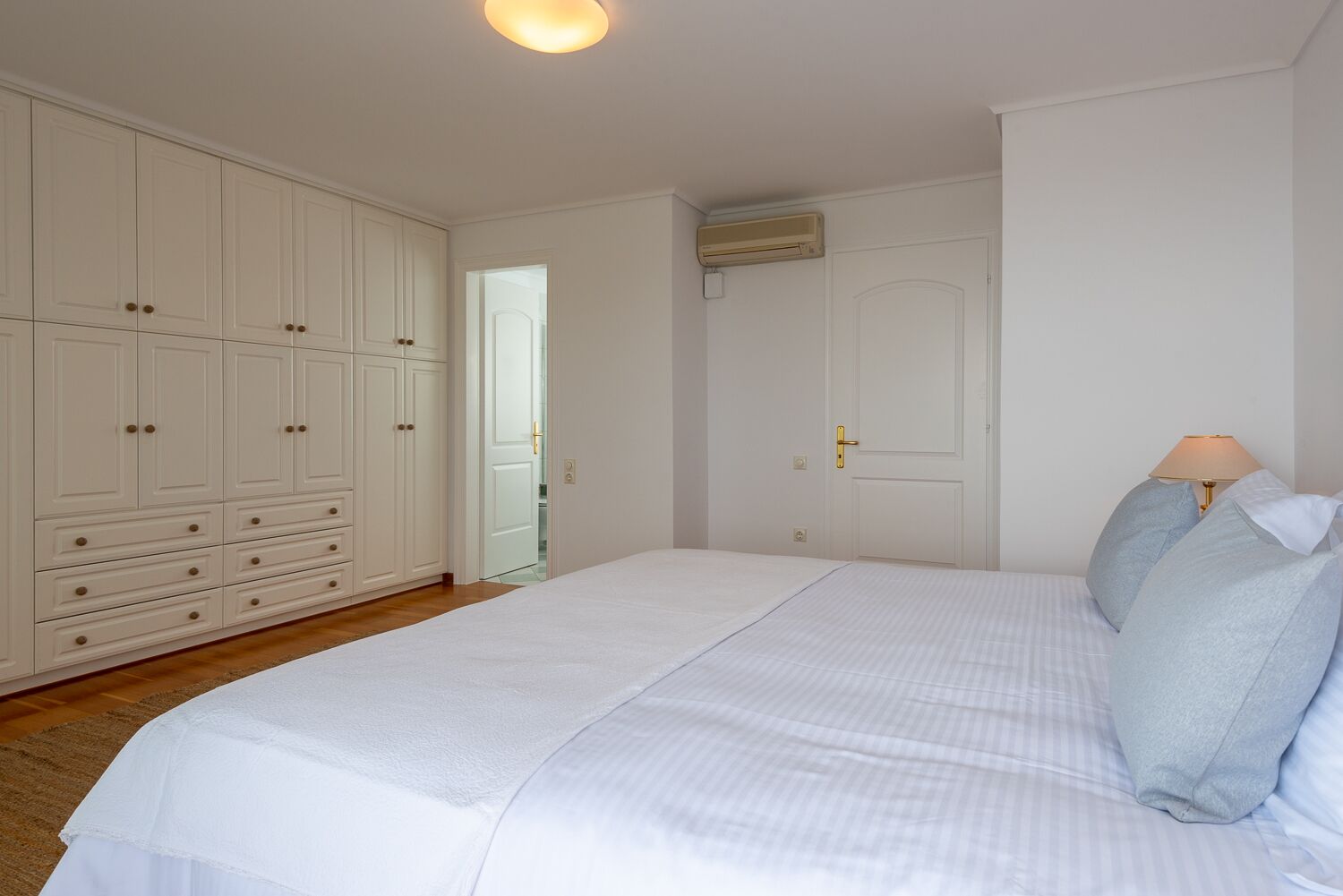 Un dormitorio con una cama grande, un armario blanco y una puerta que da a otra habitación.