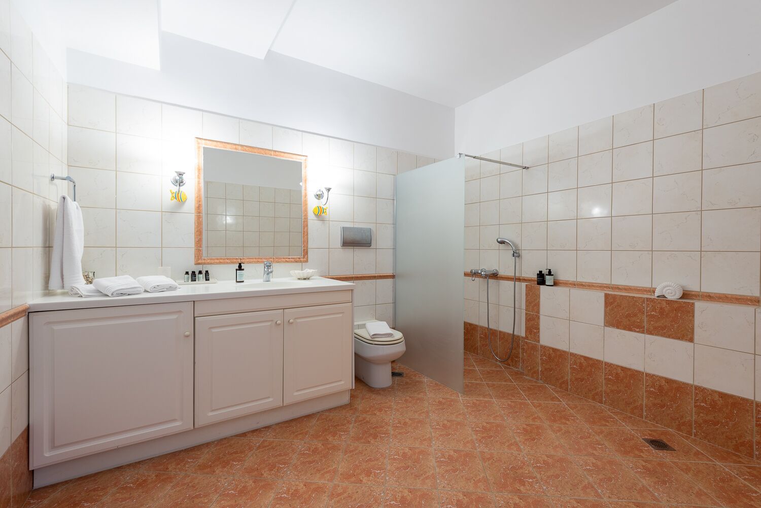 Een moderne badkamer met een grote spiegel, toilet, wastafel en douche.