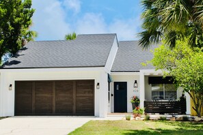 A modern two-story house with a garage, a front door, and a small porch with seating.