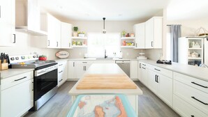 Une cuisine moderne avec des meubles blancs, un îlot central et un four encastré.