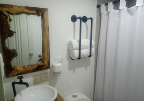 A bathroom with a wooden-framed mirror, a white sink, a toilet, and a towel rack with towels. - Hotel Momotus Cocora (Salento)