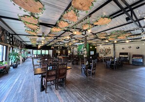 A spacious restaurant with wooden tables and chairs, hanging wooden planters with green leaves, and a rustic ceiling. - Hotel Momotus Cocora (Salento)