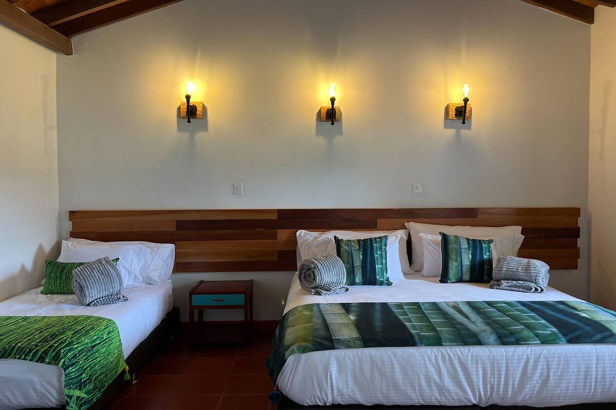 A hotel room with two beds, wooden headboards, and wall-mounted lights.