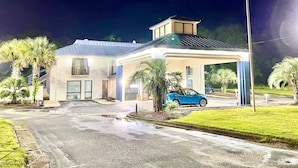 A two-story house with a covered driveway and a blue car parked outside. - Bayou Inn & Suites (Bayou La Batre)