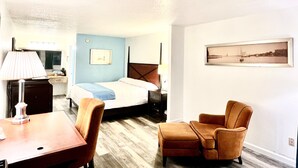 A hotel room with a bed, a desk, a chair, a lamp, a dresser, and a picture on the wall. - Bayou Inn & Suites (Bayou La Batre)