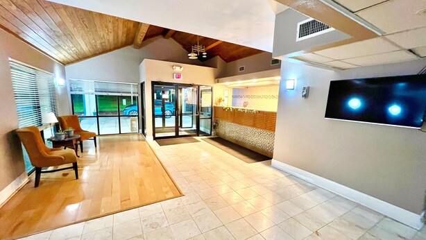 A spacious lobby with a wooden ceiling, a reception desk, and a large screen. - Bayou Inn & Suites (Bayou La Batre)