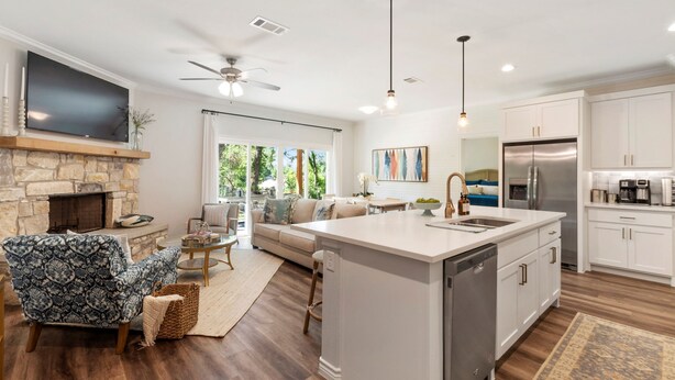 A modern kitchen with a central island, white cabinetry, and a built-in refrigerator.