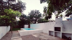 A backyard with a swimming pool, a barbecue area, and a white wall. - Resting house with pool! near the Media Luna Spring (Ciudad Fernández)