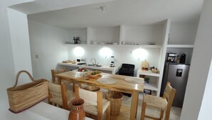 A compact kitchen with white walls, a wooden dining table, and a built-in refrigerator. - Resting house with pool! near the Media Luna Spring (Ciudad Fernández)