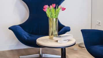 A modern room with a round table, a blue chair, and a vase with flowers.