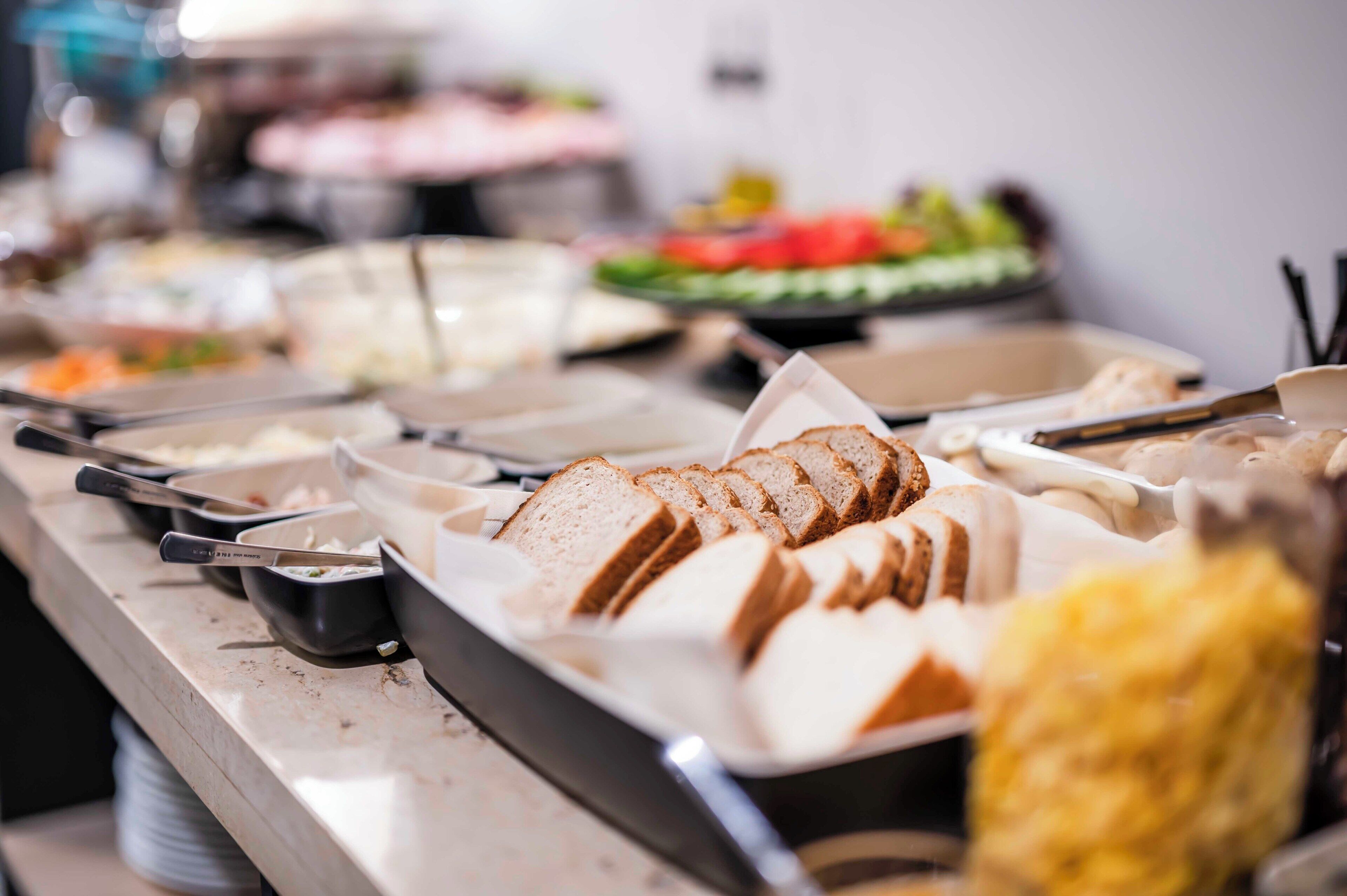 A buffet with various food items including sliced bread, salads, and other dishes.