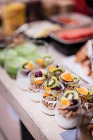Ein Buffet mit verschiedenen Speisen, darunter Obst und Granola-Parfaits.