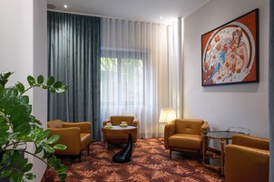 A hotel room with a large window, a painting, and a plant.