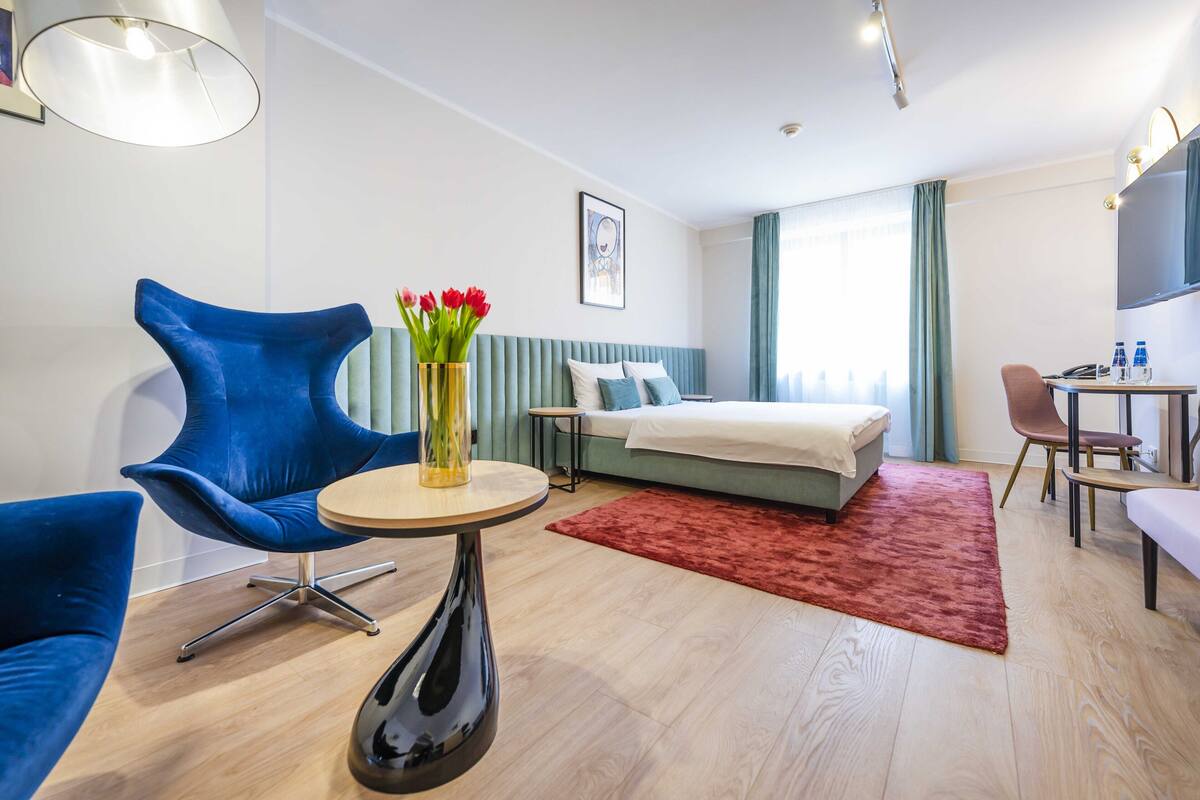 Una habitación de hotel moderna con una cama, un escritorio, una silla y una mesa redonda.