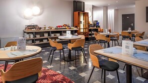 Un comedor moderno con mesas redondas, sillas y una barra de buffet.