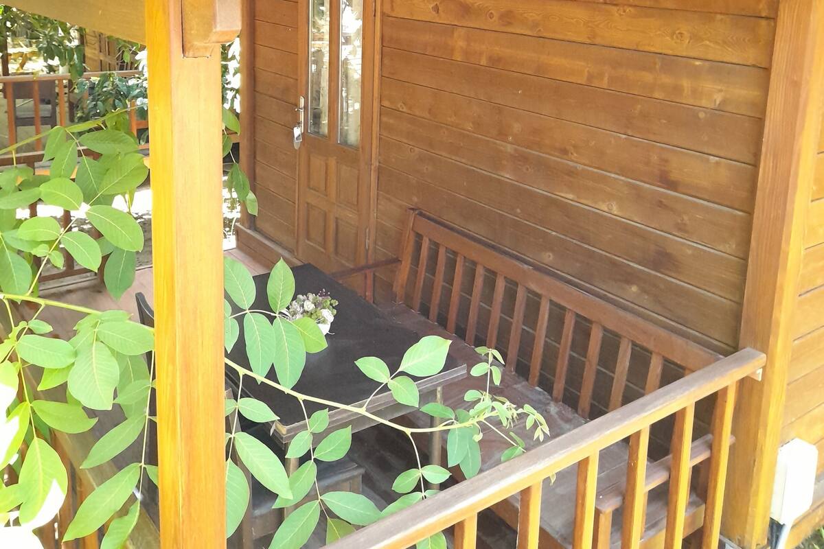 A wooden cabin with a porch, a bench, and a door.