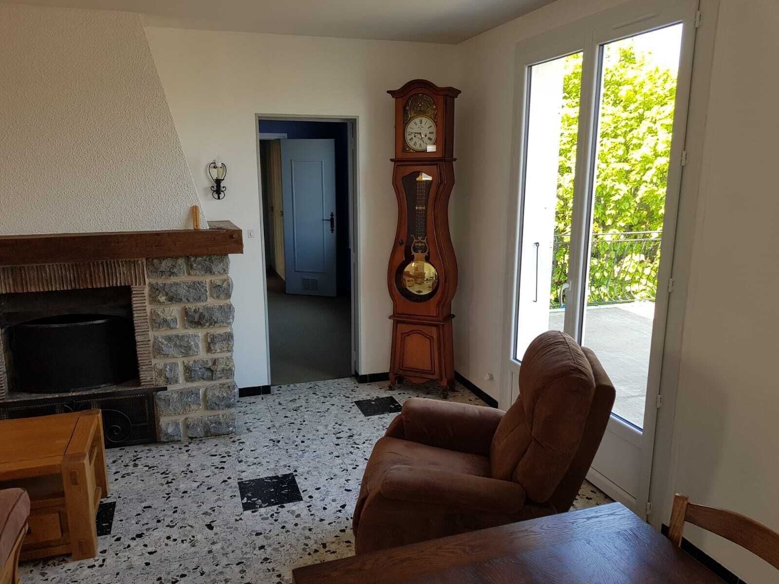 A living room with a stone fireplace, a wooden armchair, and a grandfather clock.