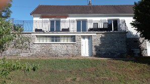 A two-story house with a stone facade, a balcony with metal railings, and a chimney. - house in the countryside in the heart of Bazois with terrace (50m2) and pleasure garden (Châtillon-en-Bazois)