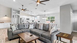A modern living room with a sectional sofa, wooden coffee table, and a dining area. - Dolphin Dreamer-Golf Cart, Pool, BEACH! (Indian Rocks Beach)