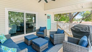 A covered patio with wicker furniture, a ceiling fan, and a sliding glass door leading to a deck. - Dolphin Dreamer-Golf Cart, Pool, BEACH! (Indian Rocks Beach)