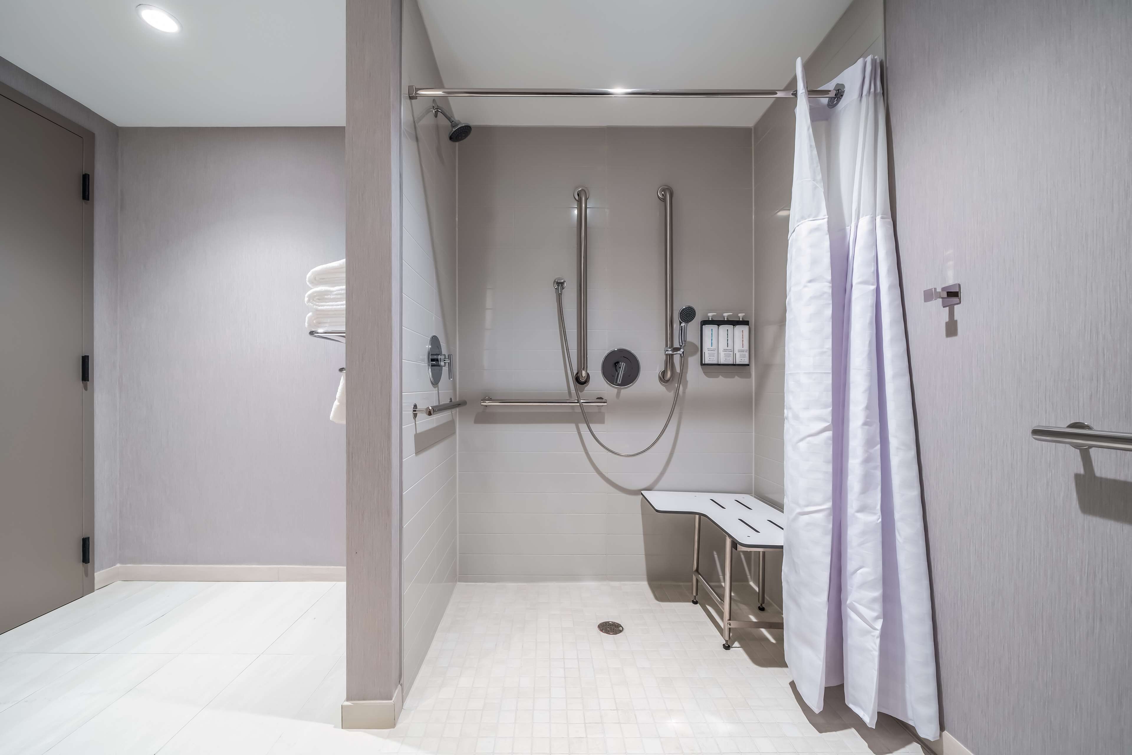 Een moderne badkamer met een inloopdouche, handgrepen en een witte wastafel.