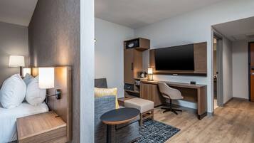 Una habitación de hotel moderna con una cama, un escritorio, una silla, un televisor y una mesita.