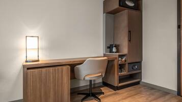 Un espacio de oficina moderno con un escritorio de madera, una silla blanca, una máquina de café y una estantería con diversos objetos.