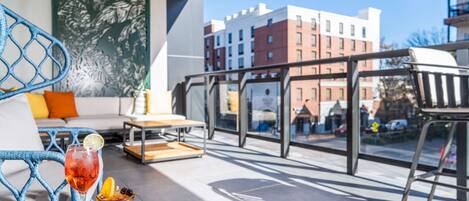A balcony with a table, chairs, and a drink.