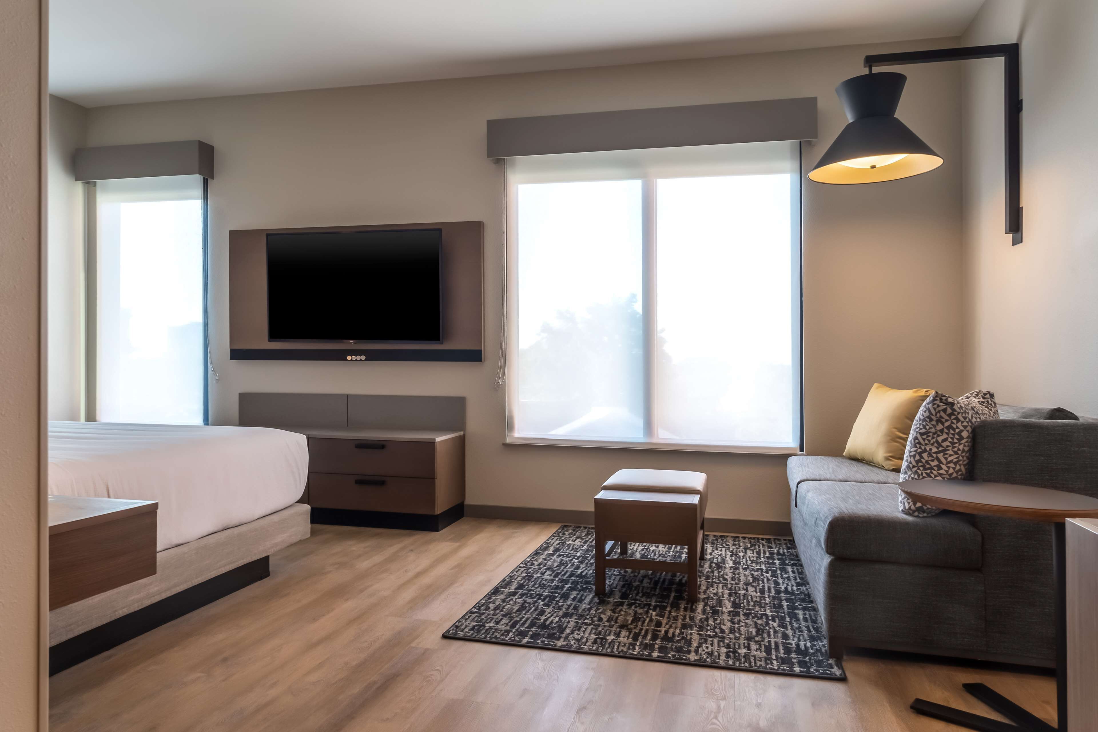 Habitació d'hotel moderna amb llit, sofà, televisió i finestra amb vistes.