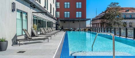 A hotel pool area with lounge chairs and a clear blue pool.