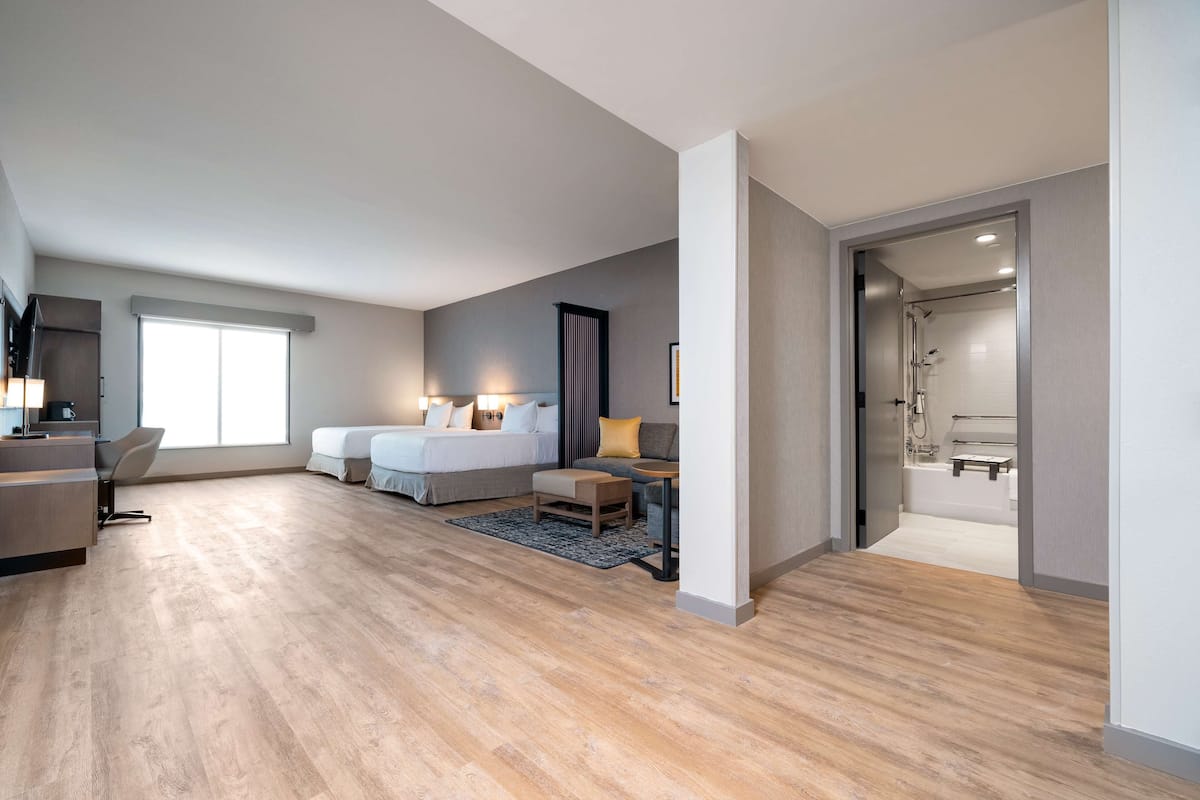 Ein modernes Hotelzimmer mit einem großen Bett, einem Schreibtisch und einer Duschkabine.