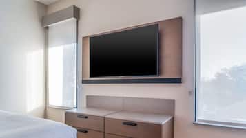 A modern bedroom with a bed, a TV mounted on the wall, and a built-in cabinet with drawers.