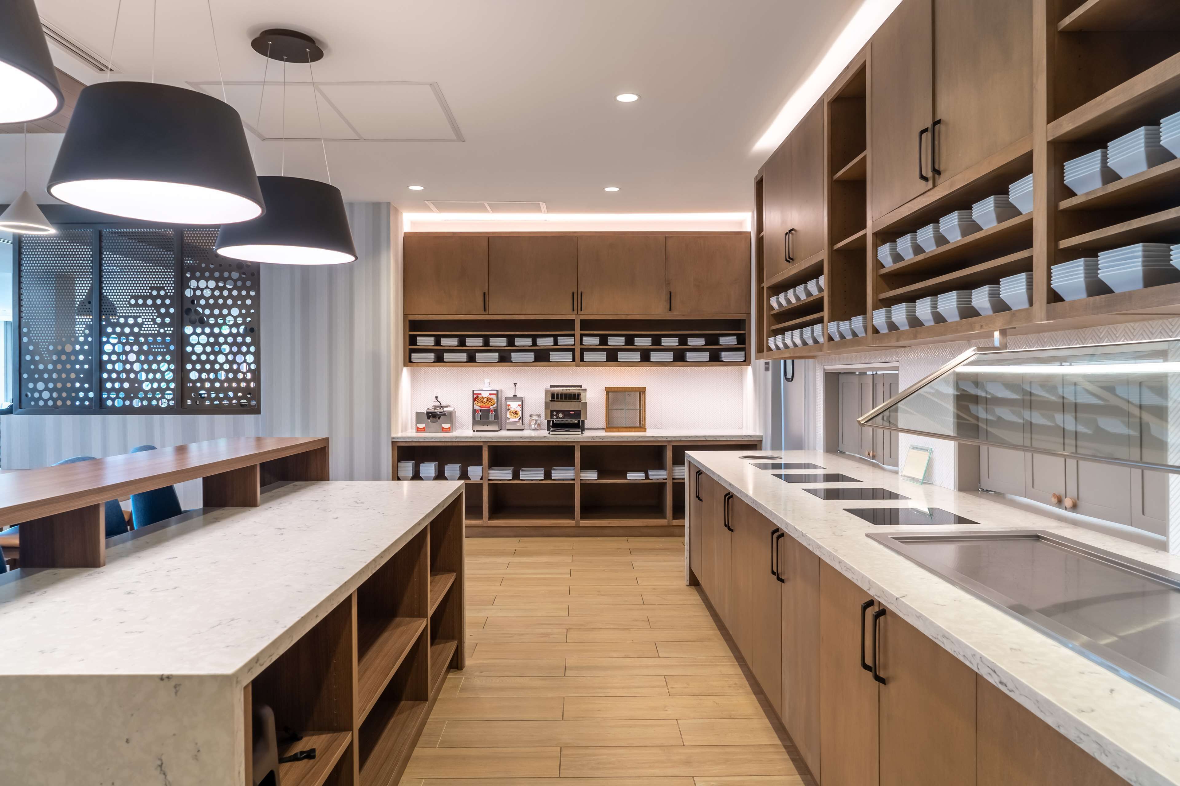 A modern kitchen with wooden cabinets, a marble countertop, and built-in appliances.
