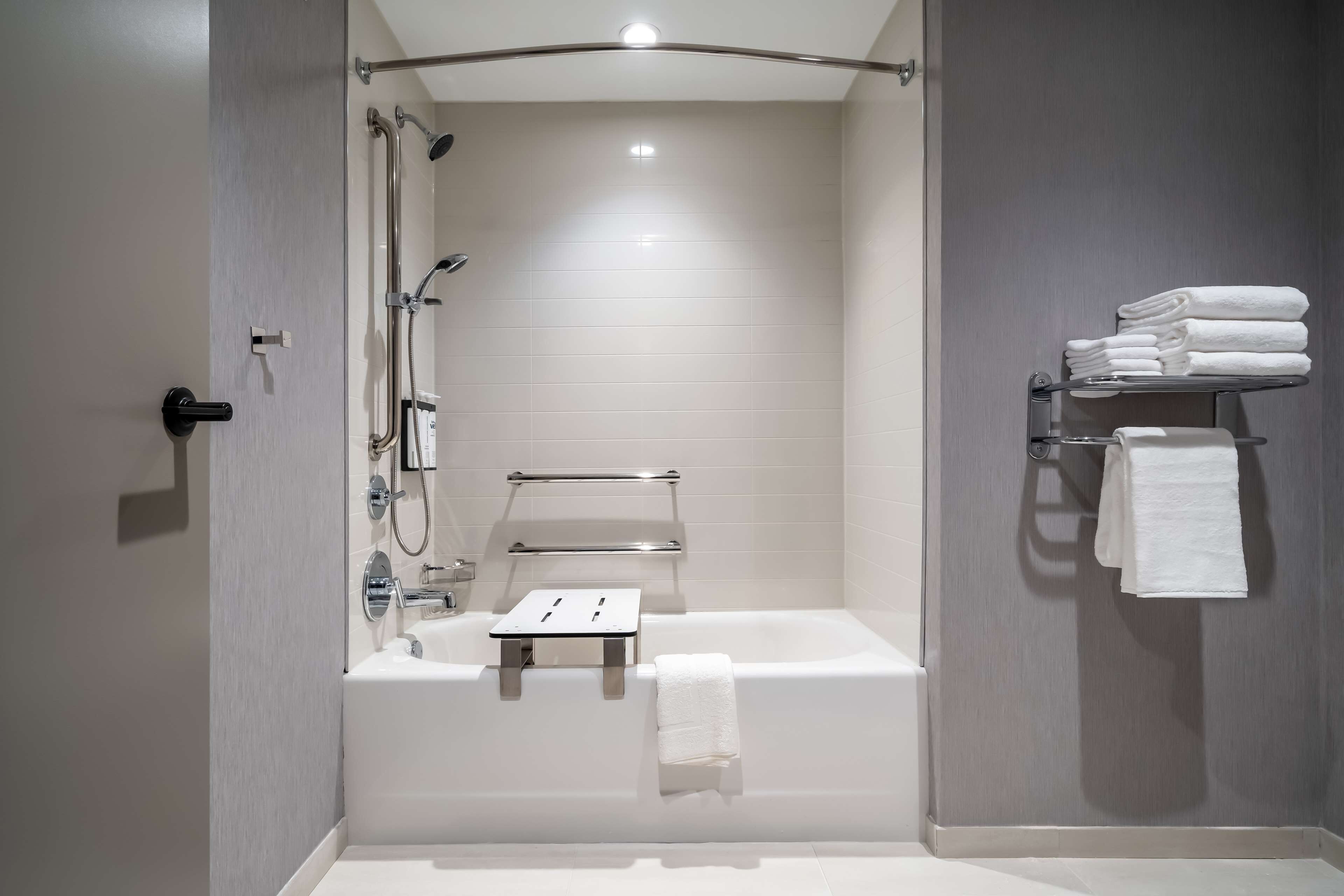 A modern bathroom with a bathtub, shower, and towel rack.