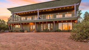 A two-story building with a balcony, large windows, and outdoor lighting. - Large Villa ~ Kings & Queens ~ Chefs Kitchen ~ Views~ Hot Tub! (Sedona)