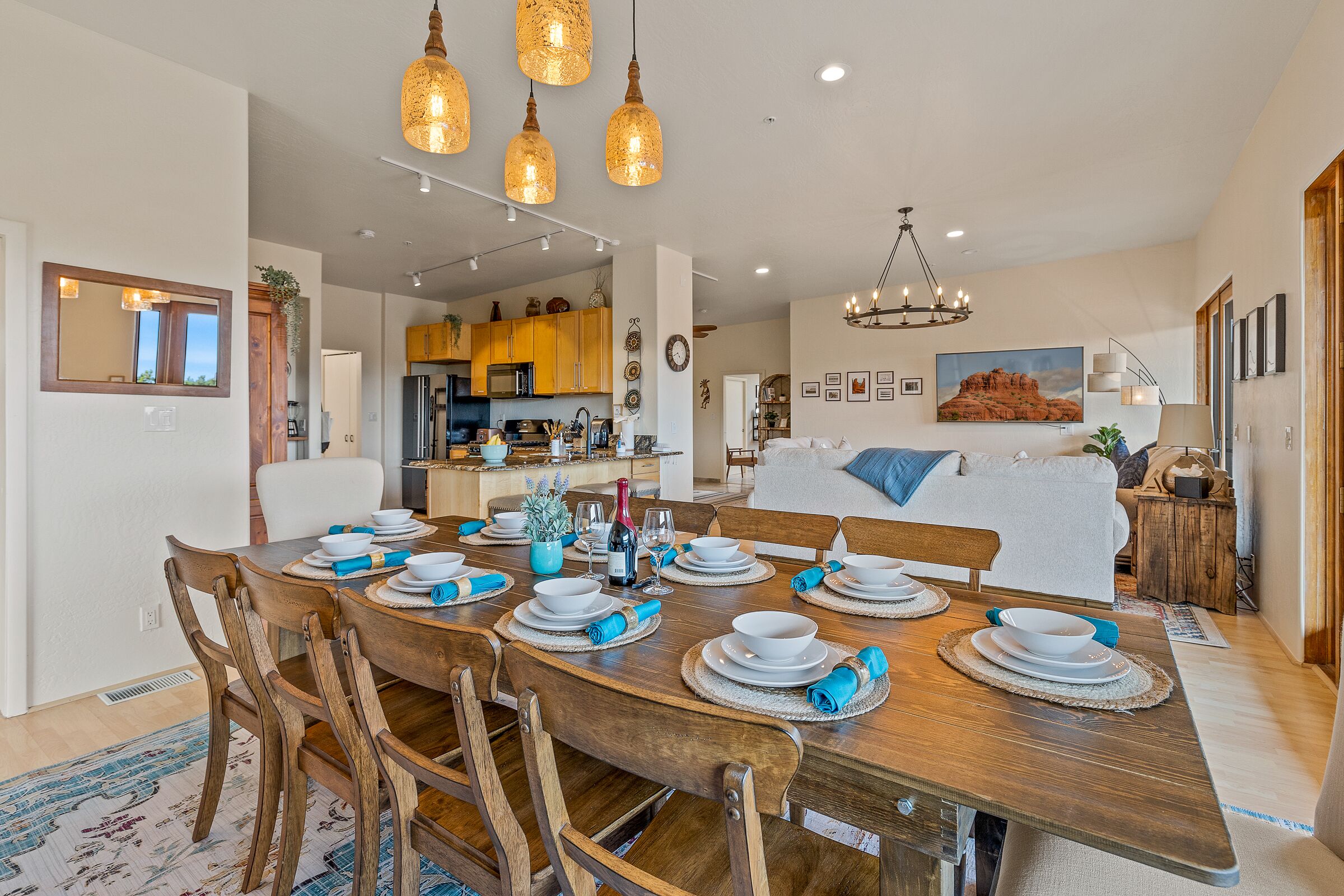 A dining area with a wooden table set for six, surrounded by wooden chairs.