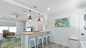 Een moderne keuken met witte kasten, een houten aanrecht en barstoelen.