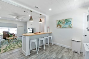 A modern kitchen with white cabinetry, a wooden countertop, and bar stools. - Paradise Palms - Tropic Suite - Heated Pool! (St. Augustine)