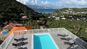 A rooftop pool with a view of a coastal town and hills. - Le Loft - Villa Ansalane (Les Trois-Îlets)