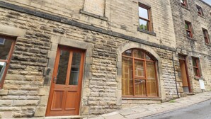 A stone building with a large arched window and a wooden door. - 1 Chews Cottage (Harrogate)