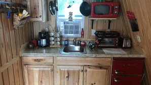 Cocina compacta con armarios de madera, un lavamanos, un refrigerador rojo, un microondas, un tostador y una cafetera.