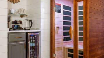 A room with a sauna, a coffee machine, and a small cabinet.
