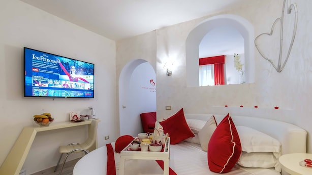A modern hotel room with a bed, a small table with a tray, a TV displaying 'Ice Princess', and a red and white color scheme. - Ripetta Luxury Del Corso (Rome)