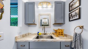 A modern kitchen with grey cabinets, a marble countertop, a sink, and a wooden utensil holder.