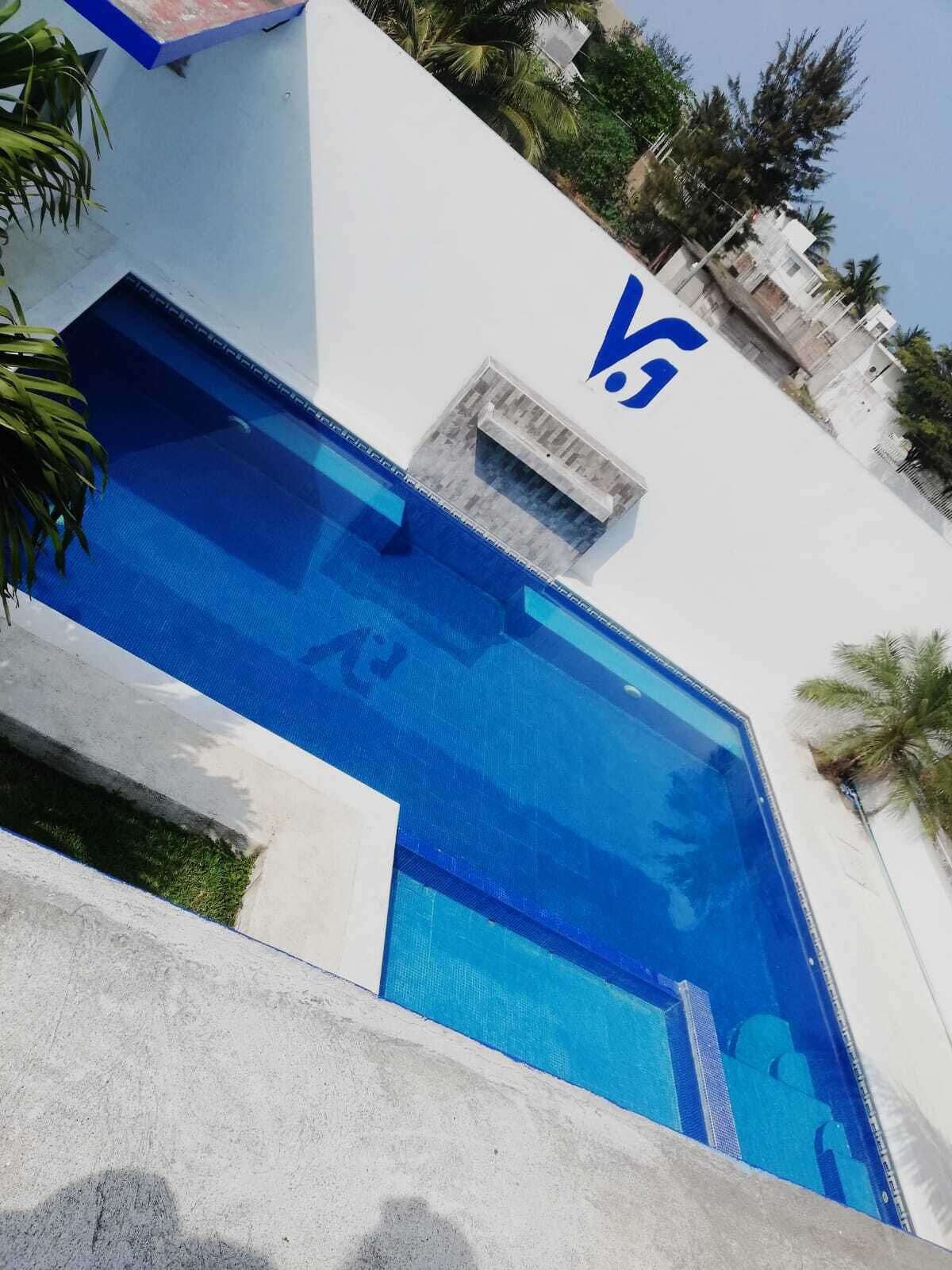 Zwembad met blauw-witte kleuren, omringd door groen en een wit gebouw met een blauw logo.